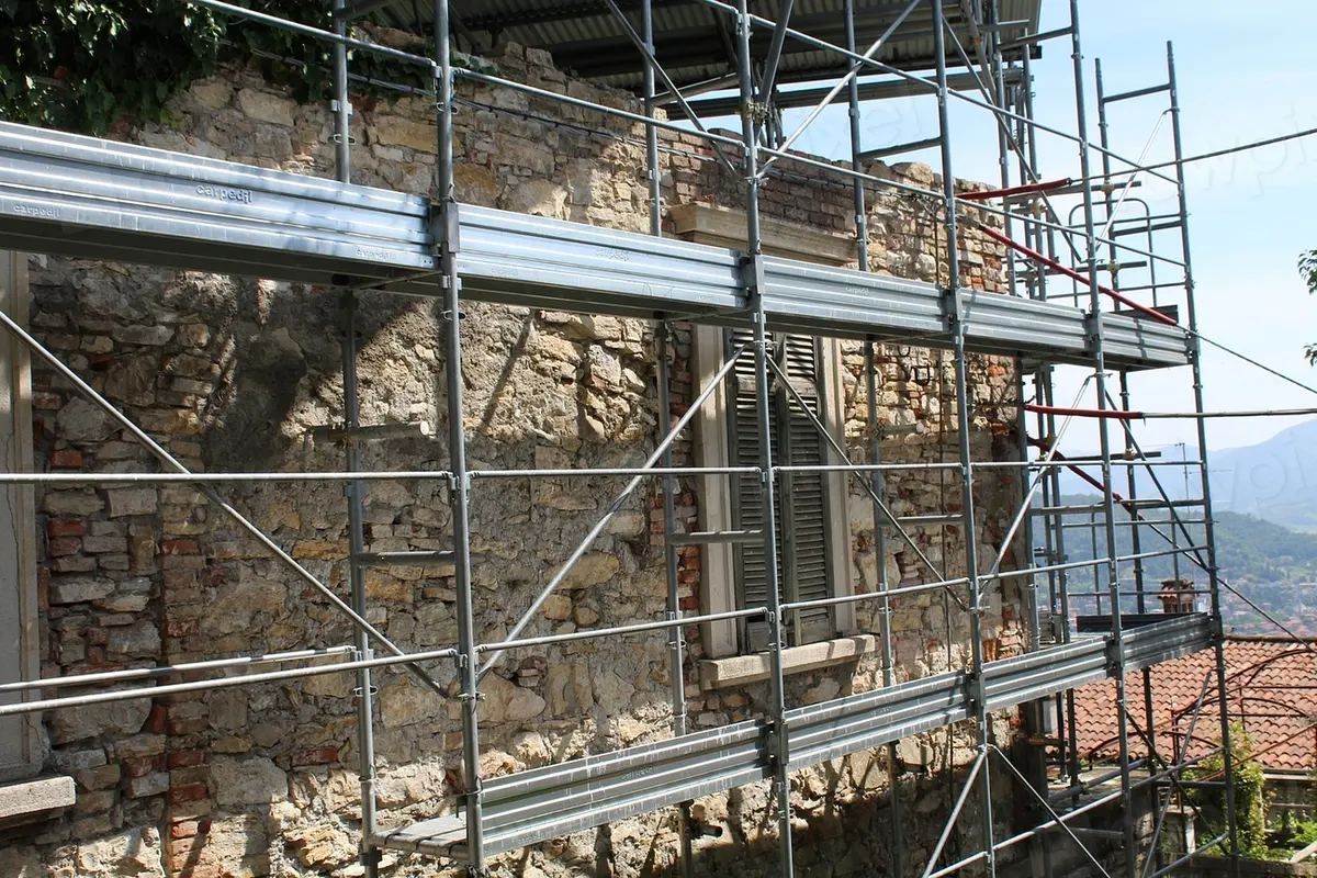 Stone building stripped back to bare masonry and wrapped in scaffolding while work continues
